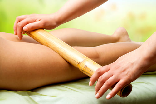 Wellnessmassagen 11 Ein Bein wird mit einem Bambusrohr massiert