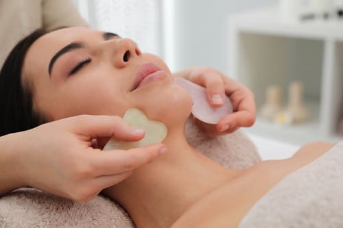 Wellnessmassagen 9 Eine Frau erhält eine Gesichtsmassage mit Gua Sha Steinen bei Claudia Göbel