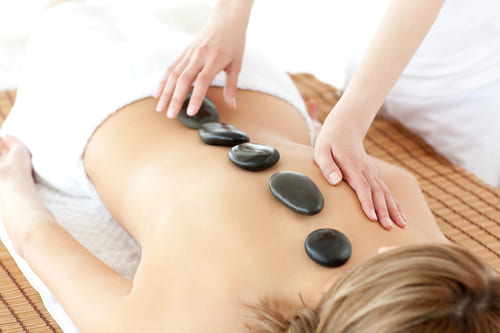 Wellnessmassagen 10 Warme Massagesteine werden auf den Rücken einer Frau gelegt